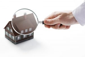 Hand holding magnifying glass over a house